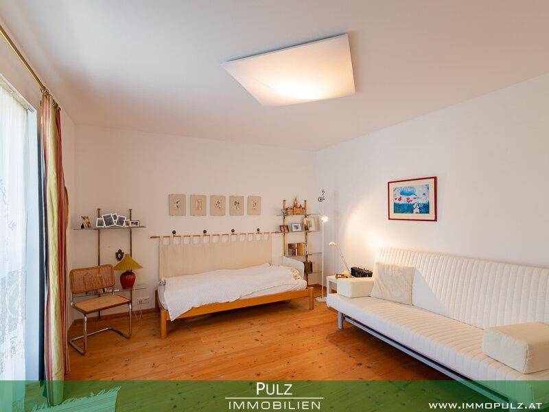 Helles Schlafzimmer mit Holzfußboden und einfacher, funktionaler Einrichtung.