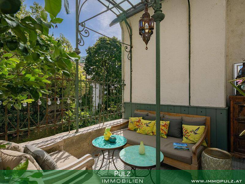 Überdachte Terrasse mit bequemen Sofas, bunten Kissen und dekorativer Laterne.