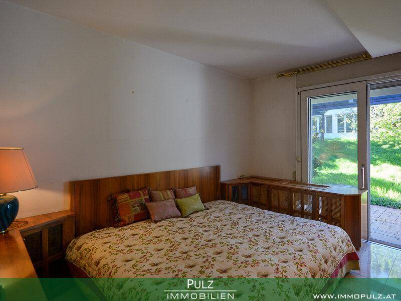 Schlafzimmer mit Doppelbett, Holzmöbeln und direktem Zugang zum Garten.