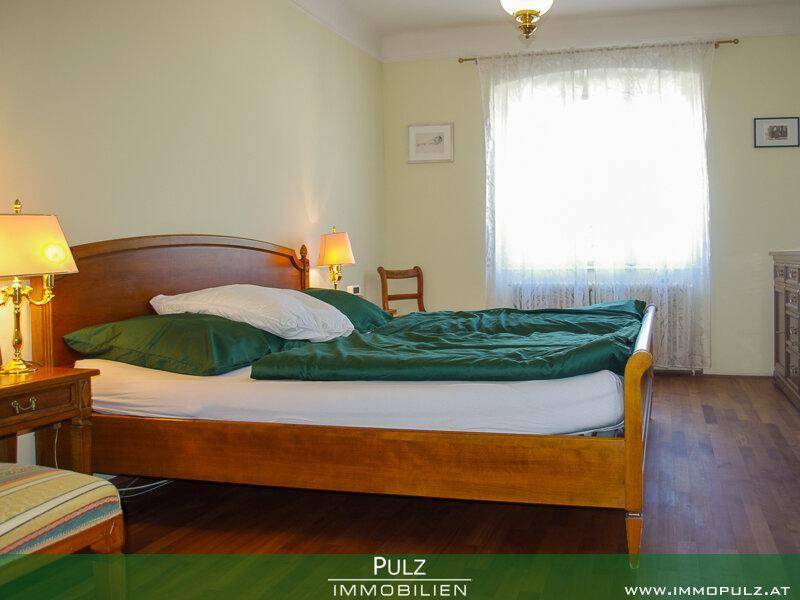 Helles Schlafzimmer mit Holzbett, Nachttischen und einem großen Fenster.