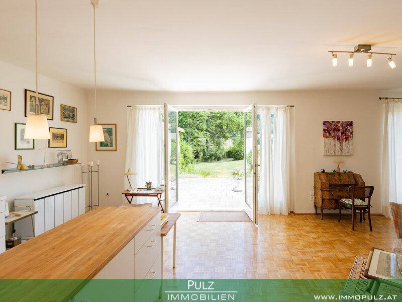 Helles Wohnzimmer mit Parkettboden und direktem Zugang zum grünen Garten.