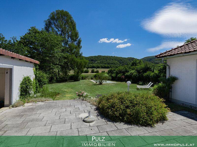 Gepflasterte Terrasse mit Blick auf den weitläufigen Garten und die hügelige Landschaft.