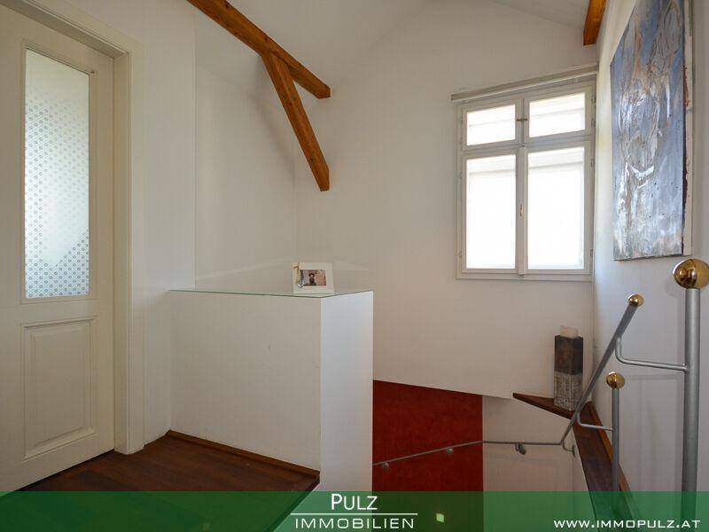 Heller Treppenabsatz mit Holzbalken, Fenster und Blick auf die untere Etage.