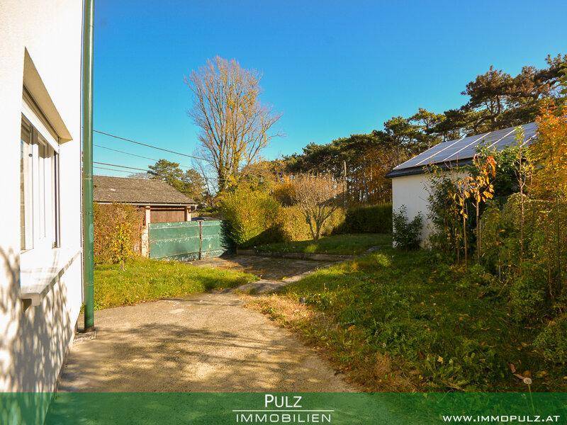 Gartenweg führt durch den Rasen, vorbei am Haus und einem Nebengebäude mit Solaranlage.