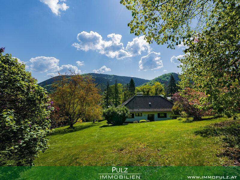 Haus eingebettet in einen großen Garten mit weitem Blick auf die umliegende Berglandschaft.