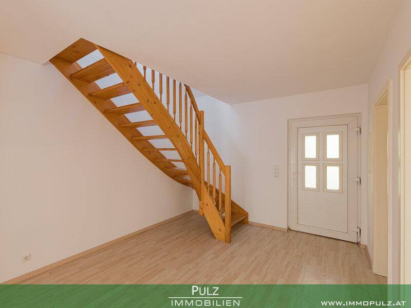 Eingangsbereich mit heller Holtreppe zum Obergeschoss und weißer Eingangstür.