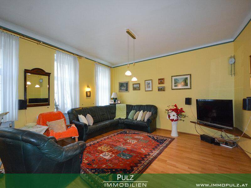 Geräumiges Wohnzimmer mit gelben Wänden, Holzboden und bequemen Ledersofas.