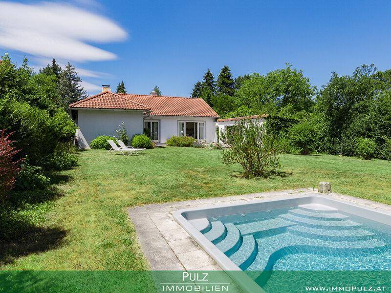 Außenansicht des Hauses mit Pool im Vordergrund und weitläufigem Gartenbereich.