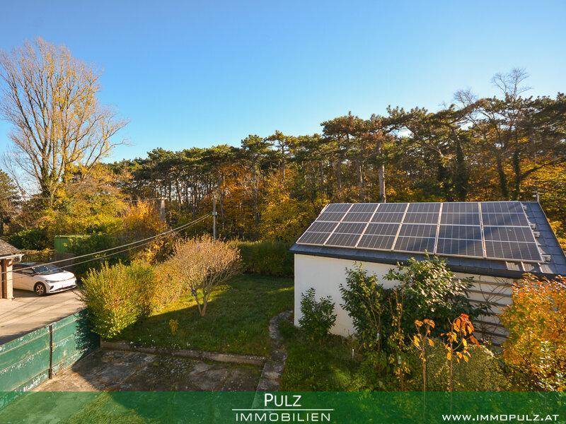 Weitläufiger Gartenbereich mit Photovoltaikanlage auf dem Nebengebäude und Baumbestand.