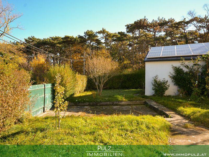 Gartenbereich mit Nebengebäude, ausgestattet mit Photovoltaikanlage auf dem Dach.