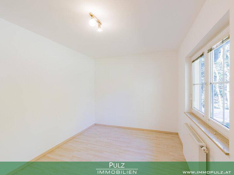 Helles, leeres Zimmer mit Holzboden und großem Fenster, bereit zur individuellen Gestaltung.