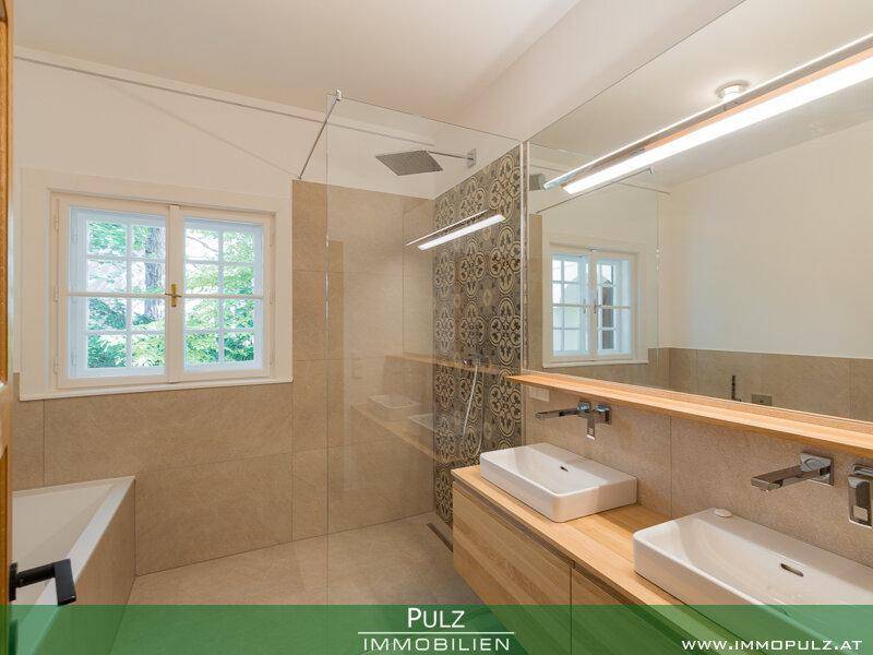 Modernes Badezimmer mit Doppelwaschbecken, großer Dusche und Fenster.