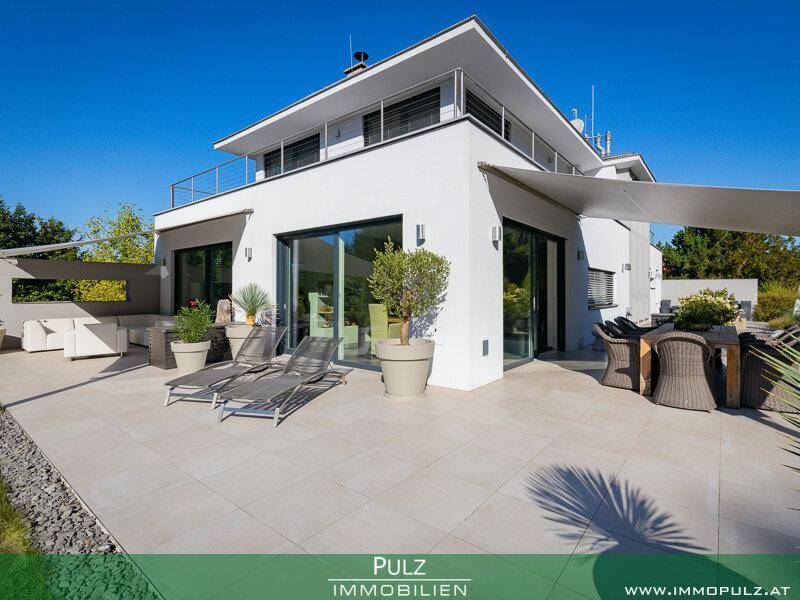 Weitläufige, geflieste Terrasse mit Sonnenliegen und Essbereich, geschützt durch ein großes Sonnensegel.