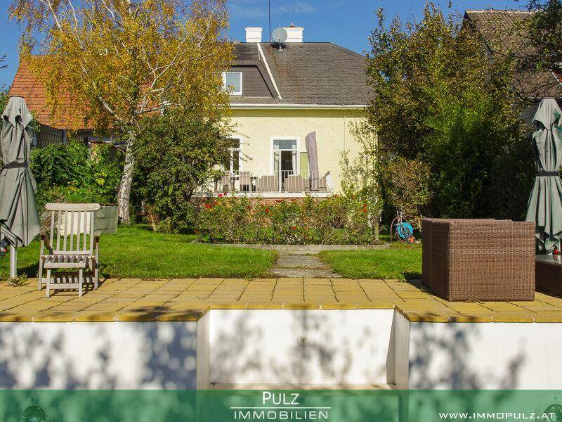 Große gepflasterte Terrasse mit Gartenmöbeln und Blick auf den Garten und das Haus.
