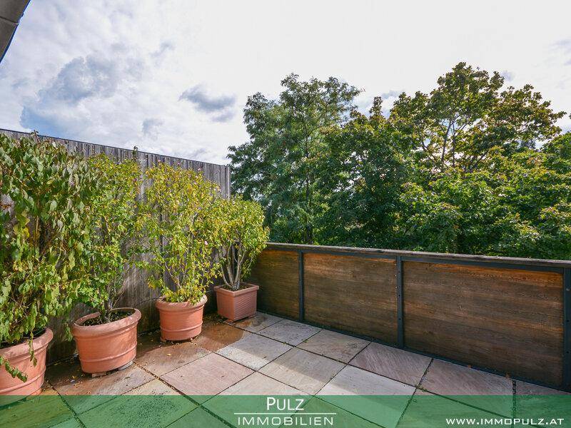 Ruhige Terrasse mit Steinplatten, Topfpflanzen und einer Holzverkleidung für Privatsphäre.