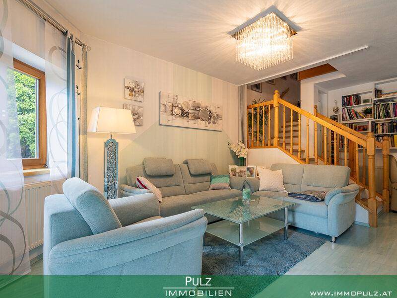 Wohnzimmer mit bequemen Sofas, Couchtisch und Blick auf die Holztreppe.