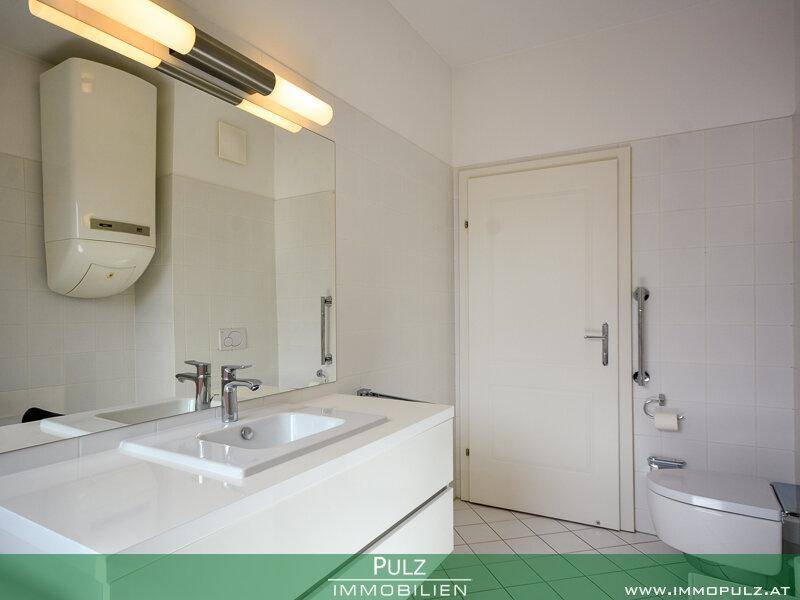 Helles Badezimmer mit modernem WC, Waschtisch und Haltegriffen für zusätzliche Sicherheit.