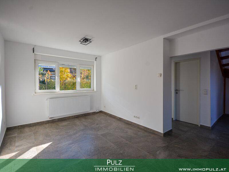 Heller, leerer Raum mit Fliesenboden, weißen Wänden und großem Fenster.