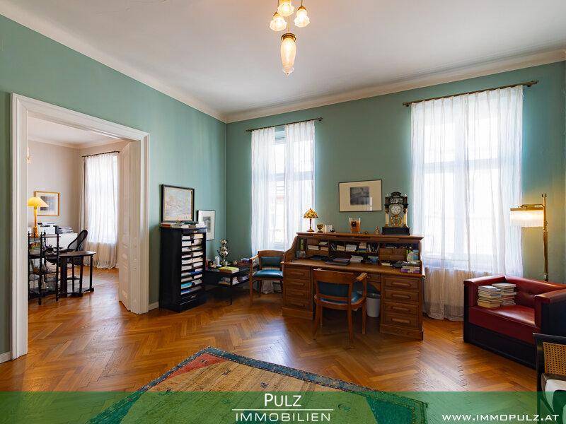 Elegantes Arbeitszimmer mit Parkettboden, Schreibtisch und hellgrünen Wänden.