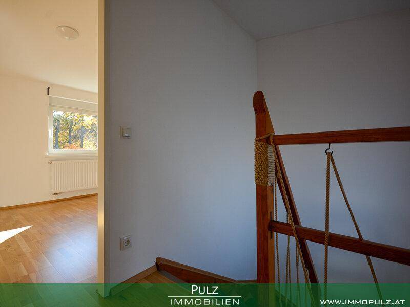 Oberer Treppenabsatz mit Holztreppe und Zugang zu einem Zimmer mit Parkettboden.