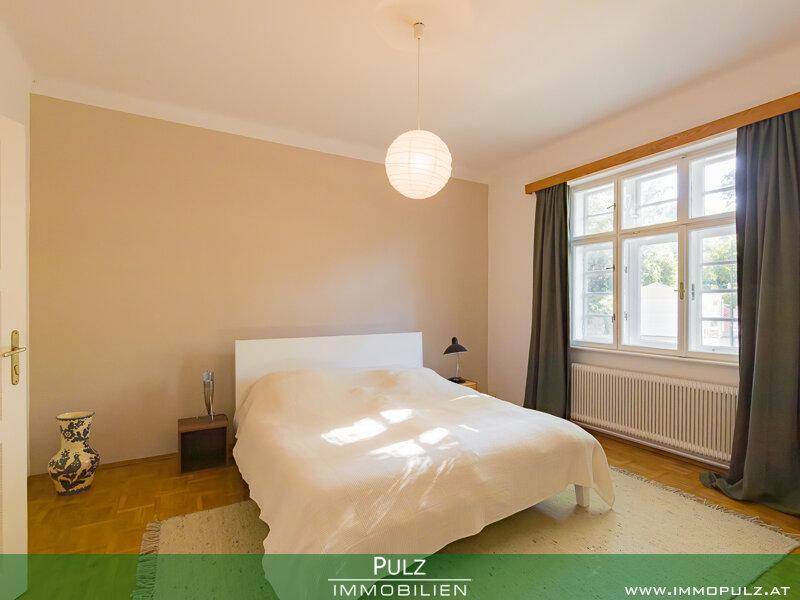 Gemütliches Schlafzimmer mit Parkettboden, großem Fenster und viel natürlichem Licht.