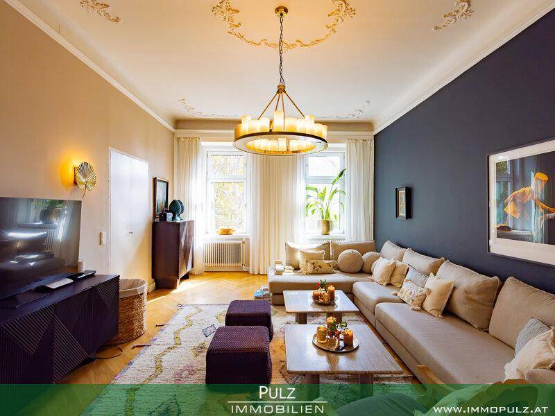 Gemütliches Wohnzimmer mit Parkettboden, Stuckdecke und großem Sofa.