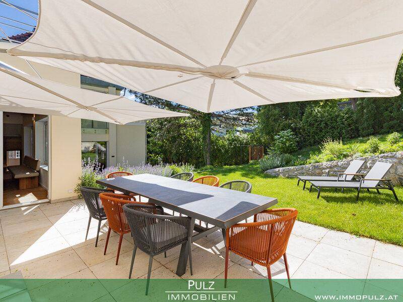 Großzügige Terrasse mit Esstisch, Sonnenschirm und Blick auf den gepflegten Garten.