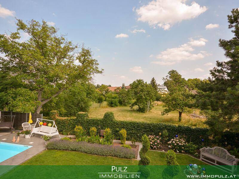 Weitläufiger Blick vom Garten über die grüne Landschaft mit Bäumen und einem Swimmingpool.
