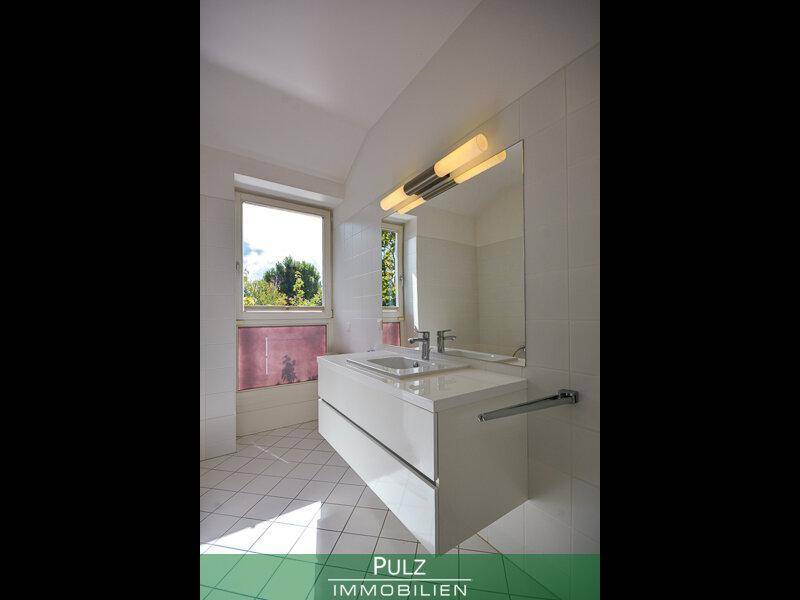 Modernes Badezimmer mit schwebendem Waschtisch, großem Spiegel und Fenster für Tageslicht.