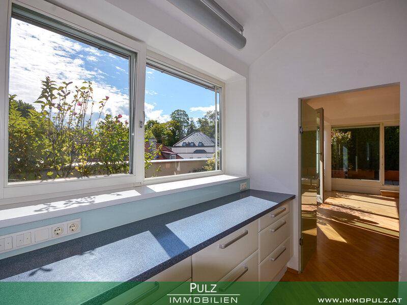 Helle Küche mit Fensterblick ins Grüne und modernen Arbeitsflächen.