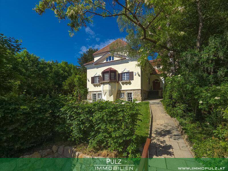 Charmante Villa, eingebettet in eine grüne Landschaft mit einem malerischen Zugangsweg.