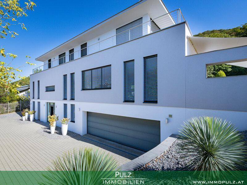 Moderne Architektur der Villa mit integrierter Garage und gepflasterter Zufahrt.
