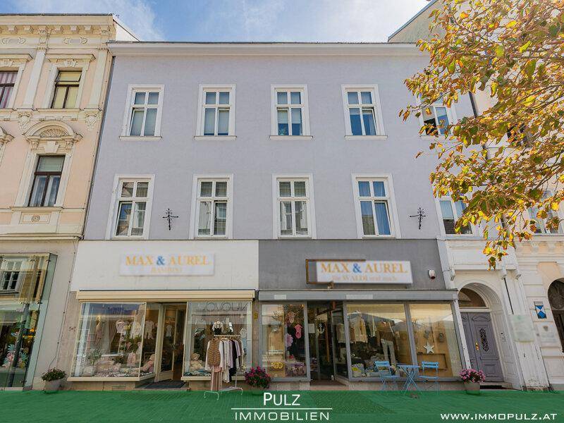 Fassade eines historischen Gebäudes mit mehreren Fenstern und Ladenfronten im Erdgeschoss.