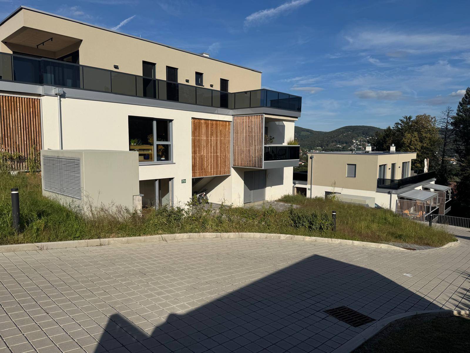 Moderne Wohnanlage mit mehreren Einheiten und Balkonen in sonniger Hanglage.