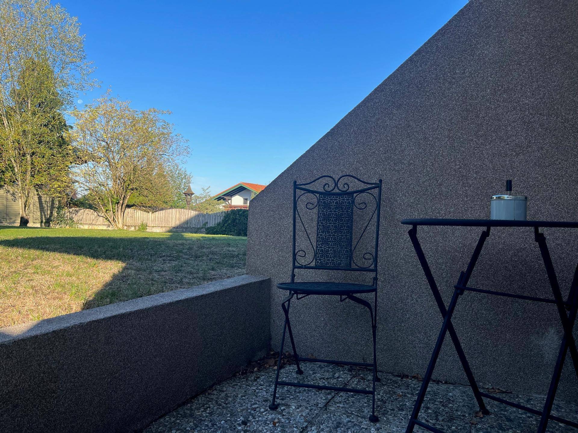 Gemütliche Terrasse mit schmiedeeisernen Möbeln und weitem Blick auf den umliegenden Garten.
