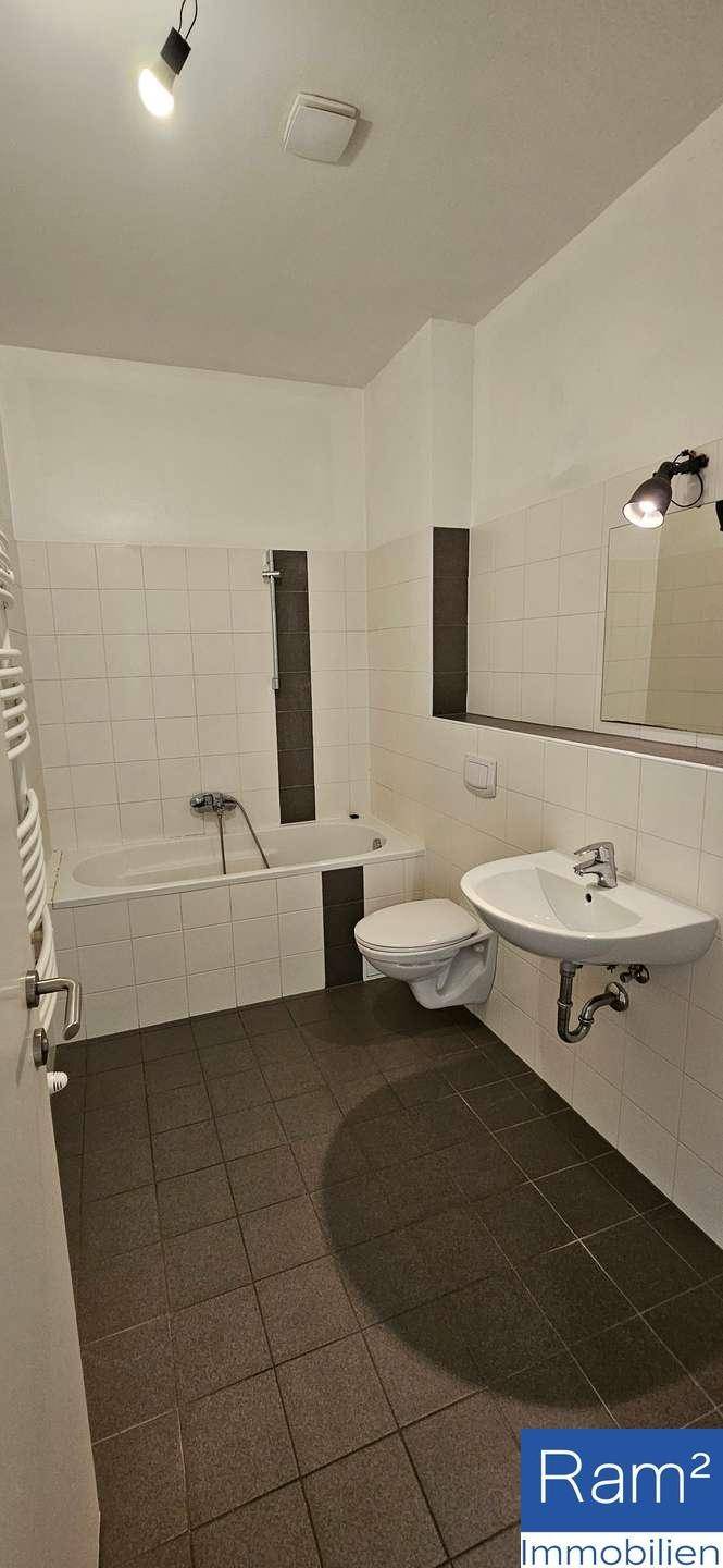 Badezimmer mit Badewanne, WC, Einzelwaschbecken und Fliesenboden.