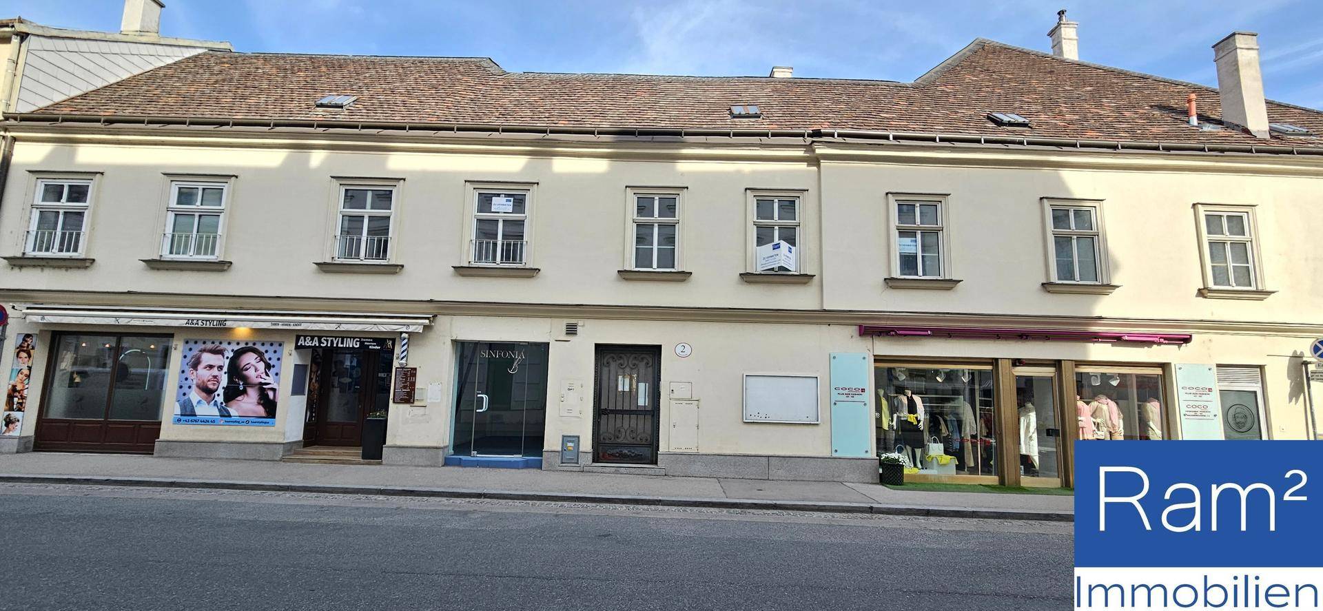 Ansicht der Gebäudefassade mit Schaufenstern im Erdgeschoss und Wohnungen darüber in der Stadt.