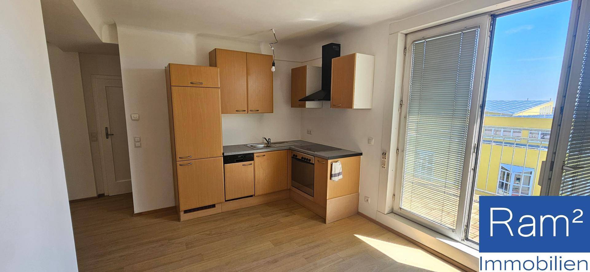 Funktionale Küche mit Holzschränken, integrierten Geräten und Zugang zu einem Balkon.