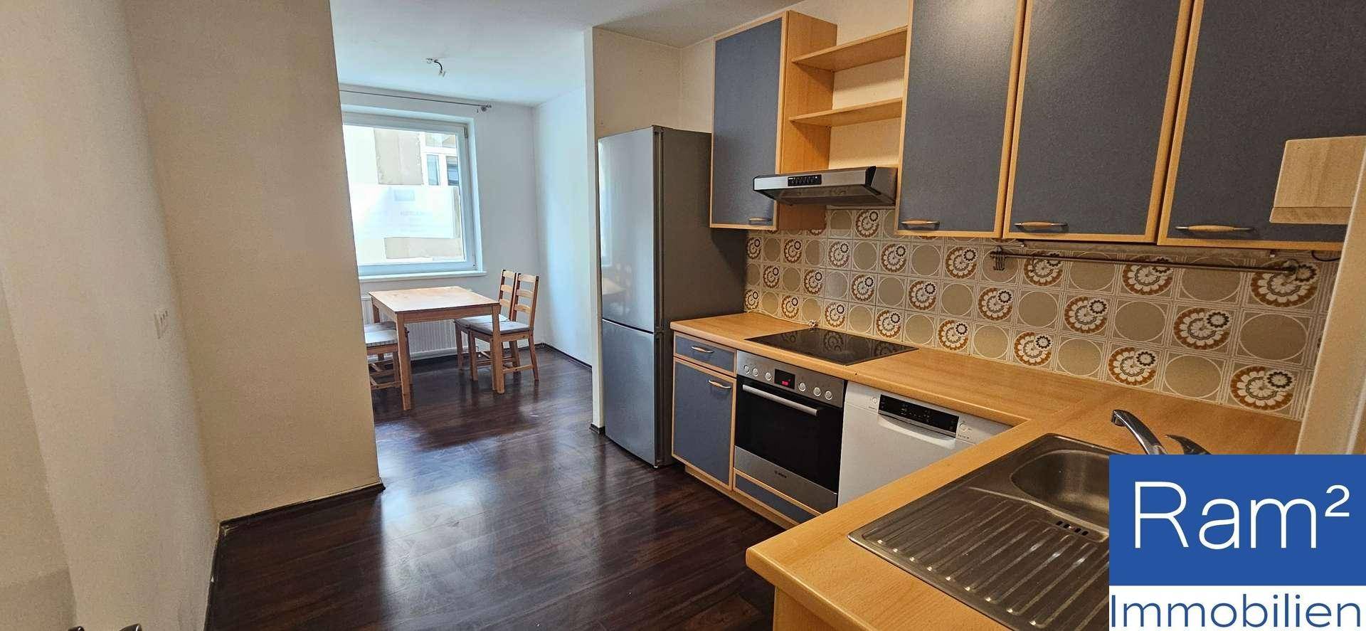 Funktionale Küche mit Einbaugeräten, dunklen Schränken und einem Essbereich am Fenster.