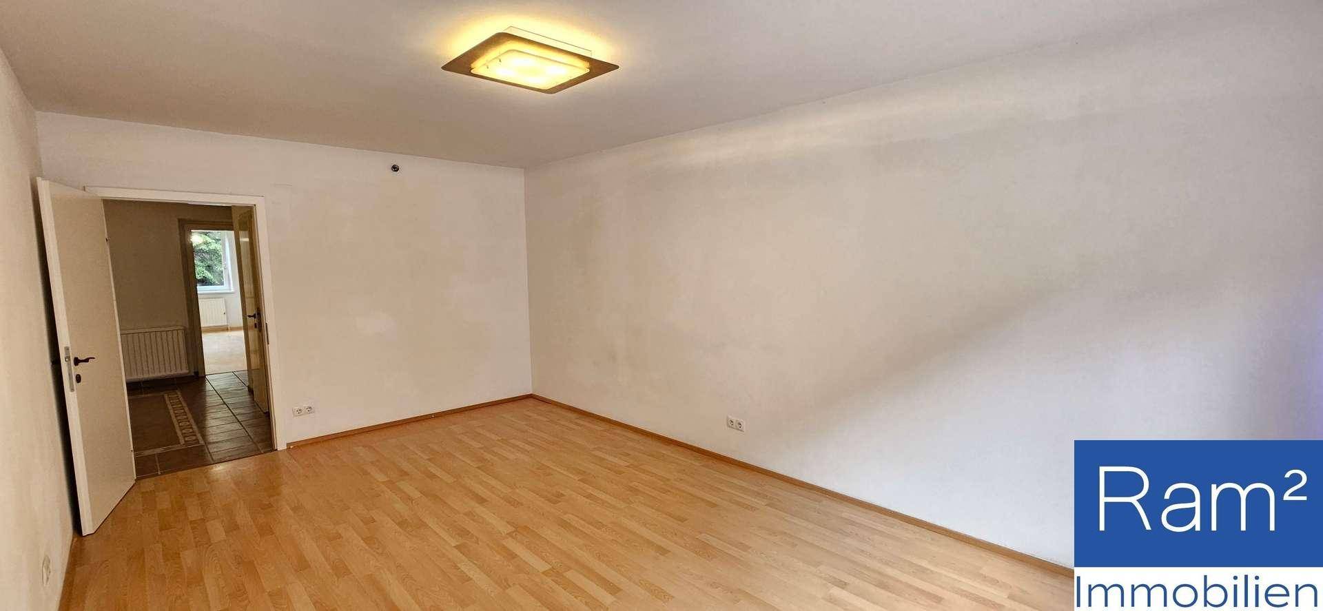 Geräumiges Zimmer mit Holzboden und Zugang zu einem weiteren Raum, hell und einladend.