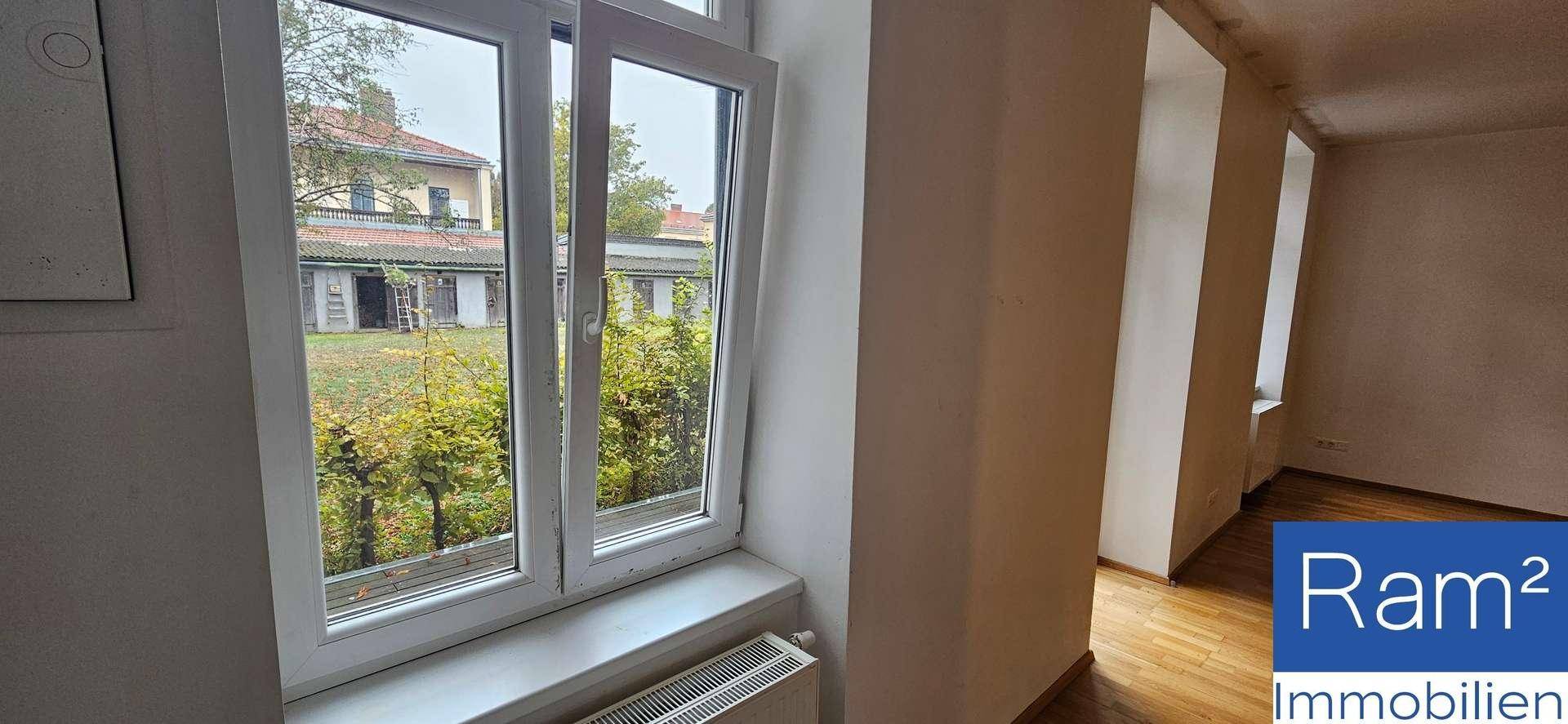 Fenster mit Blick auf den grünen Außenbereich und die umliegenden Gebäude.