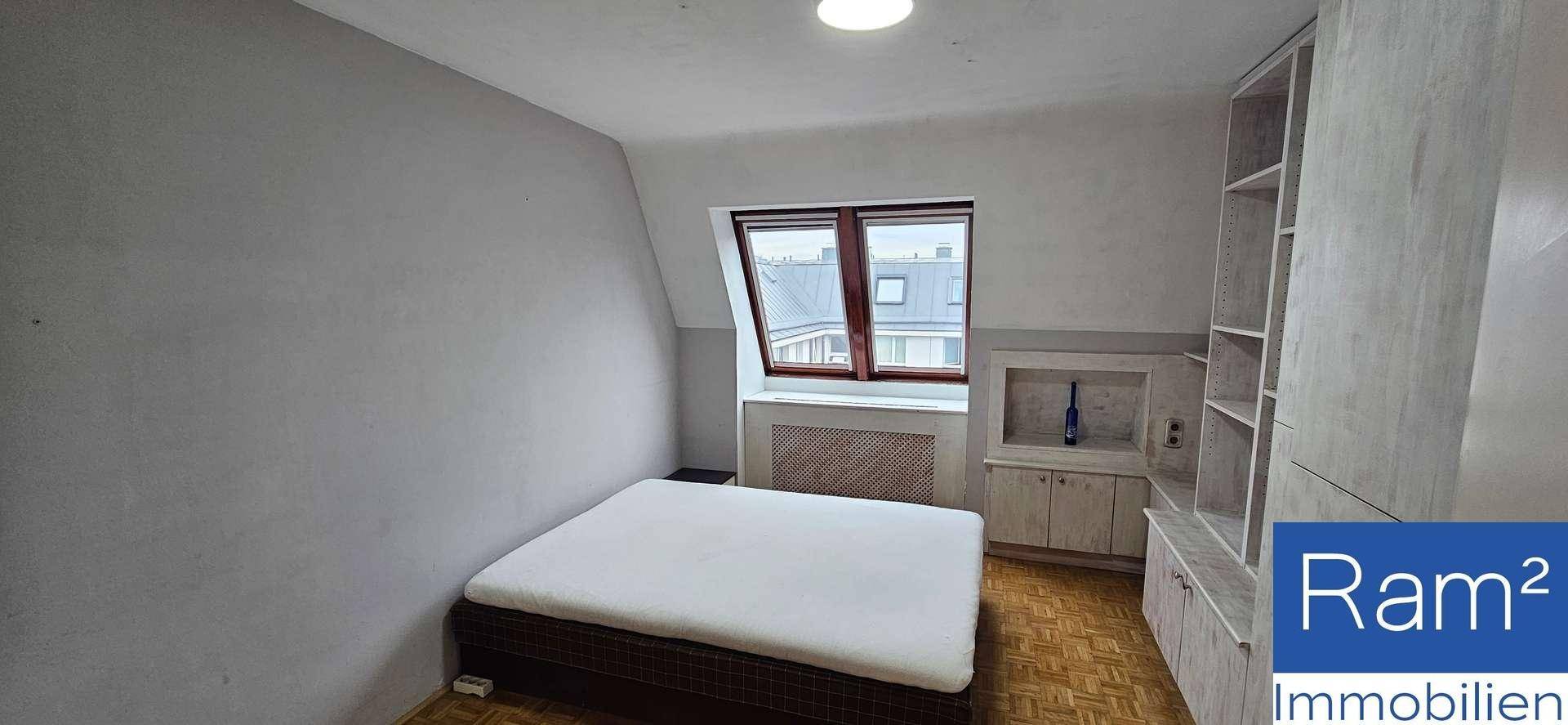 Schlafzimmer mit Holzboden, Bett und einem Fenster in der Dachschräge.