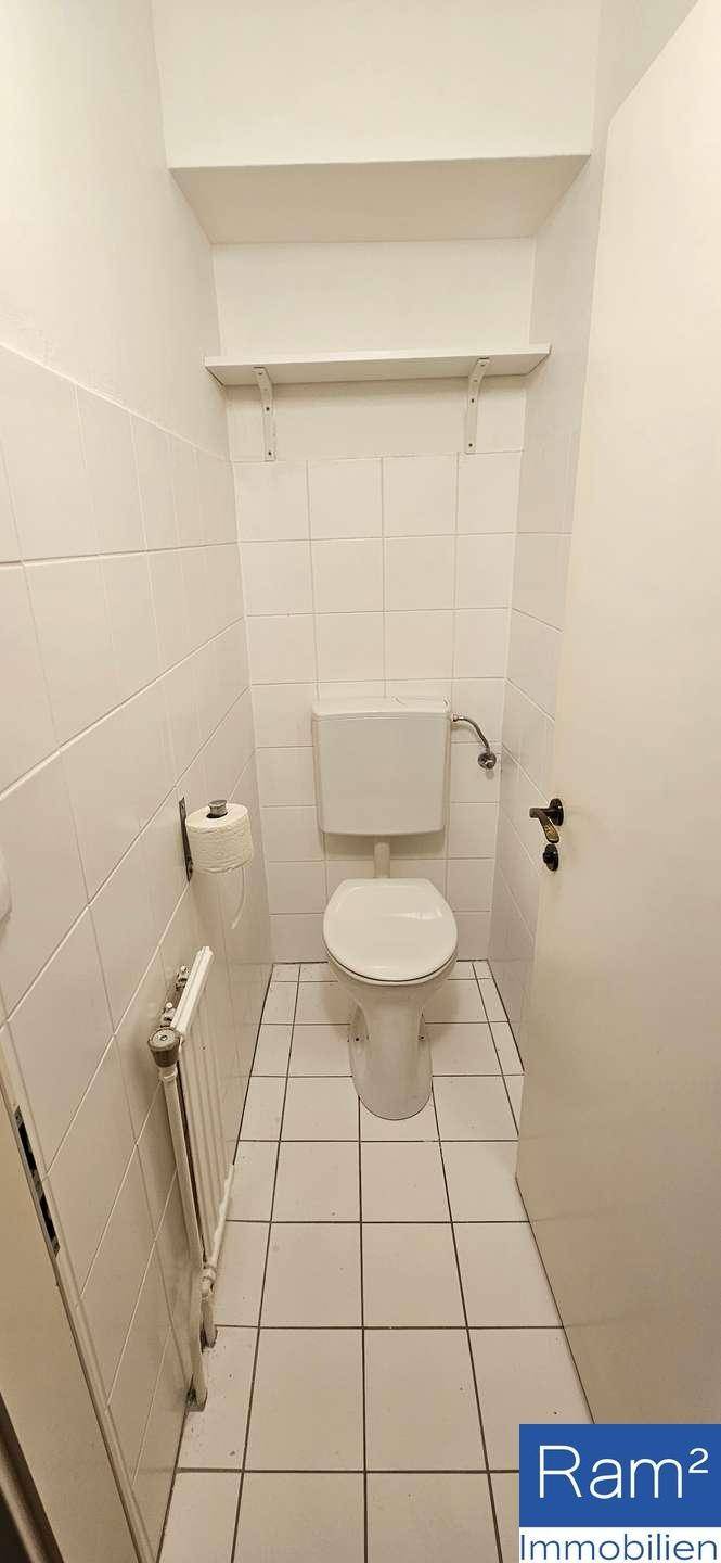 Kleines Gäste-WC mit weiß gefliesten Wänden und einem wandmontierten WC.