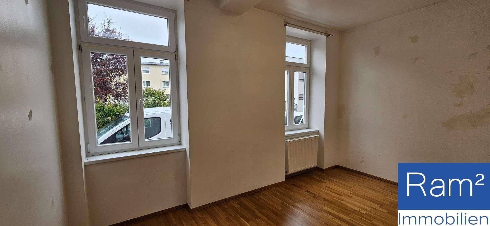 Geräumiges Zimmer mit zwei Fenstern, Parkettboden und viel Tageslicht.