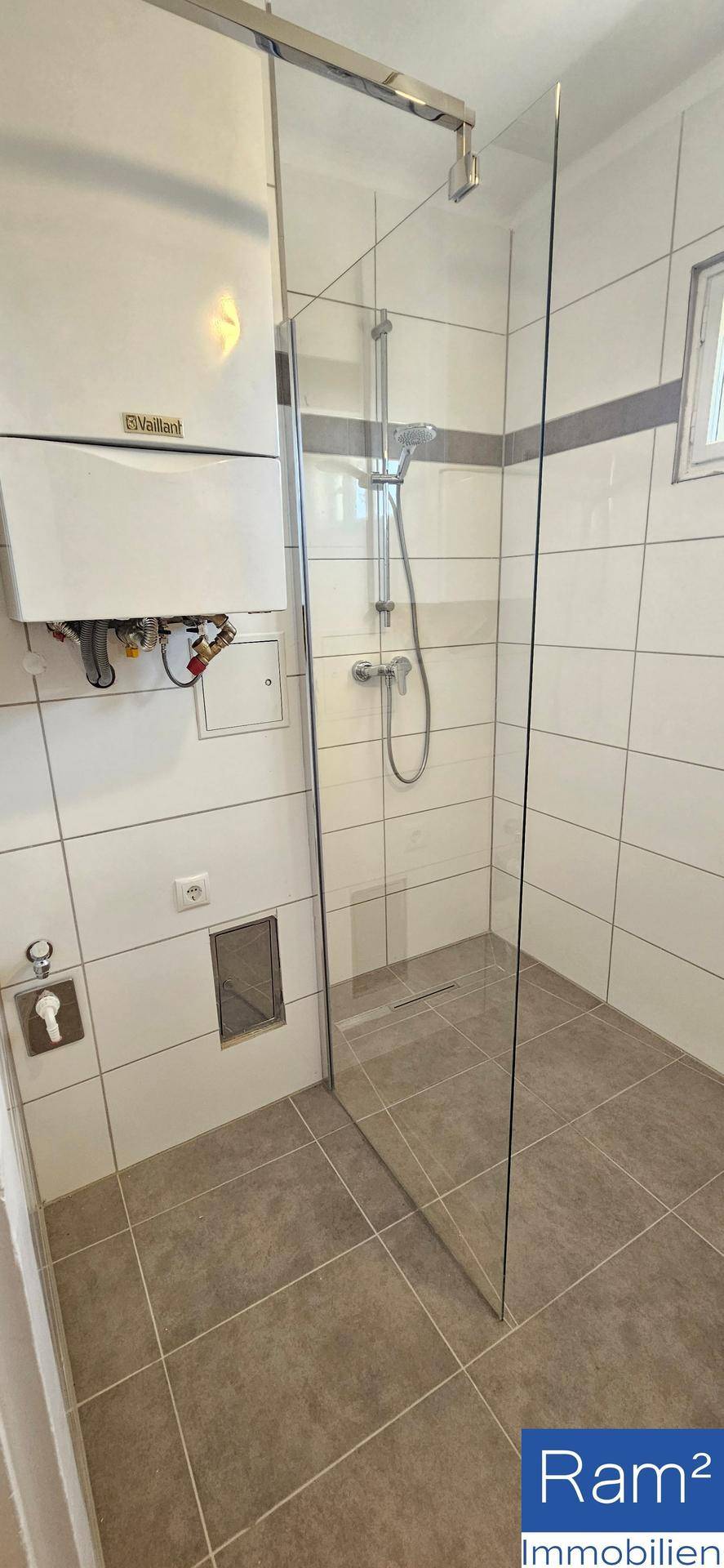Modernes Badezimmer mit begehbarer Dusche, weißen Fliesen und Wandheizung.