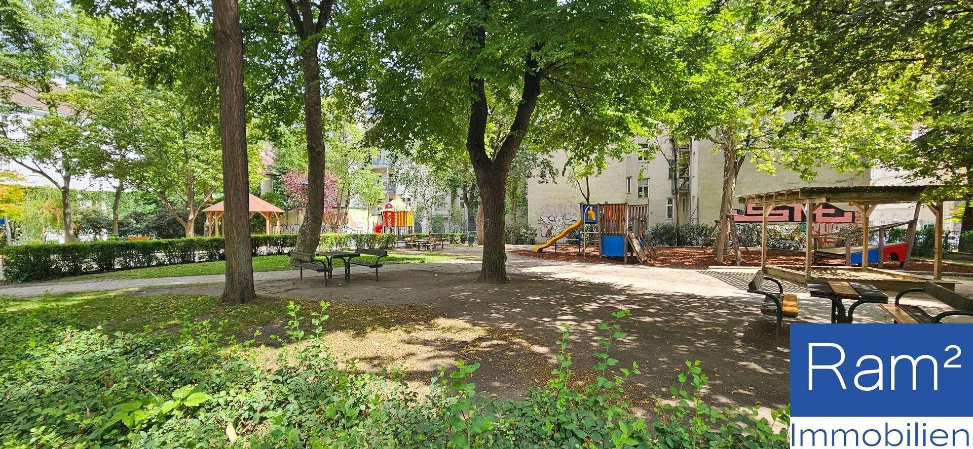 Grüner Parkbereich mit Spielplatzgeräten, Bäumen und Bänken, ideal für Familien.