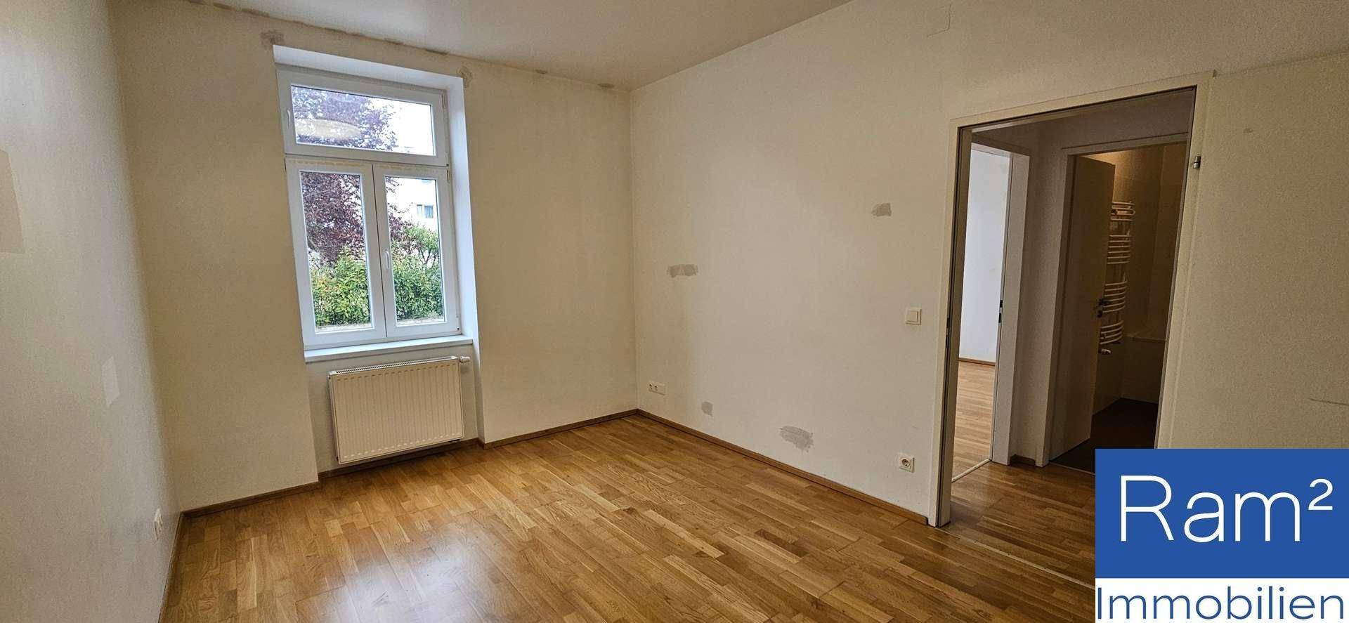 Leeres Zimmer mit Parkettboden, Fenster und Heizkörper, bereit zur individuellen Gestaltung.