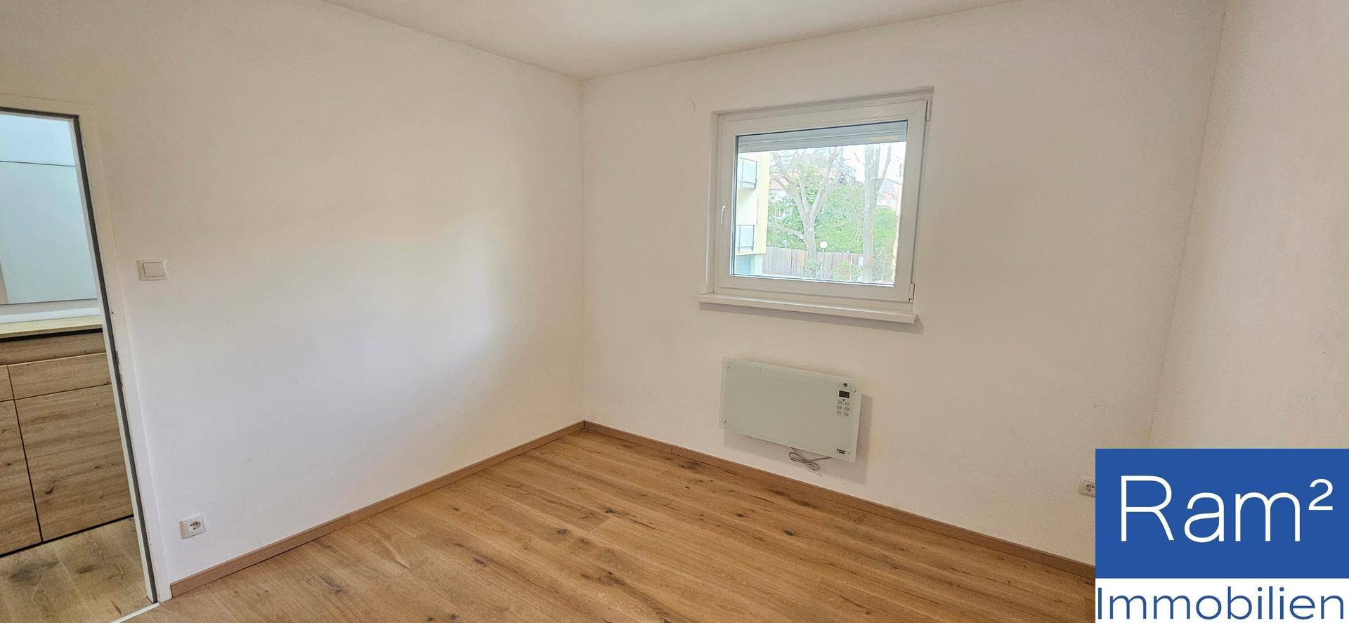 Geräumiges Zimmer mit Holzfußboden und viel Tageslicht durch das Fenster.