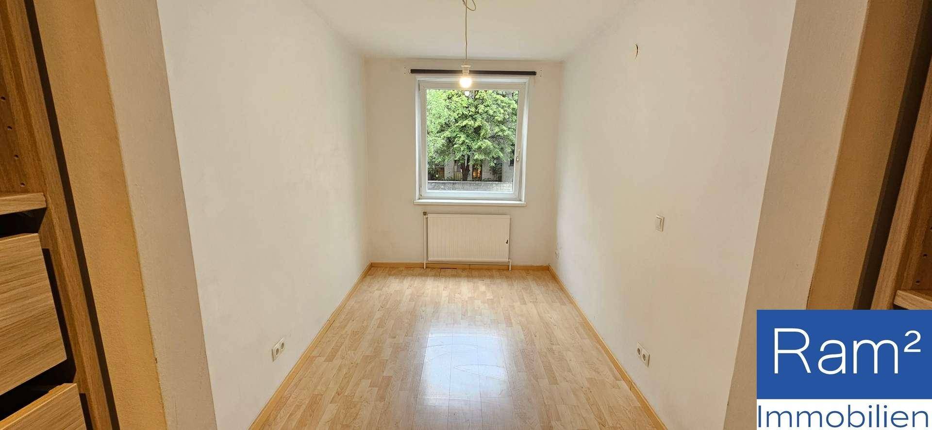 Helles Zimmer mit Holzboden und einem Fenster, das viel Tageslicht hereinlässt.