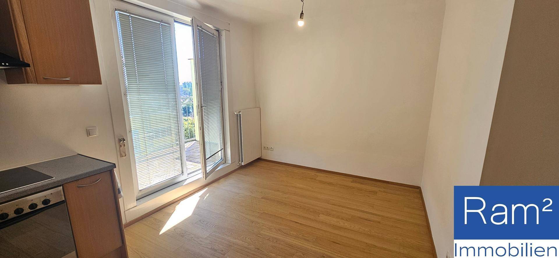 Heller Raum mit Laminatboden und direktem Zugang zum Balkon, ideal für einen offenen Wohnbereich.